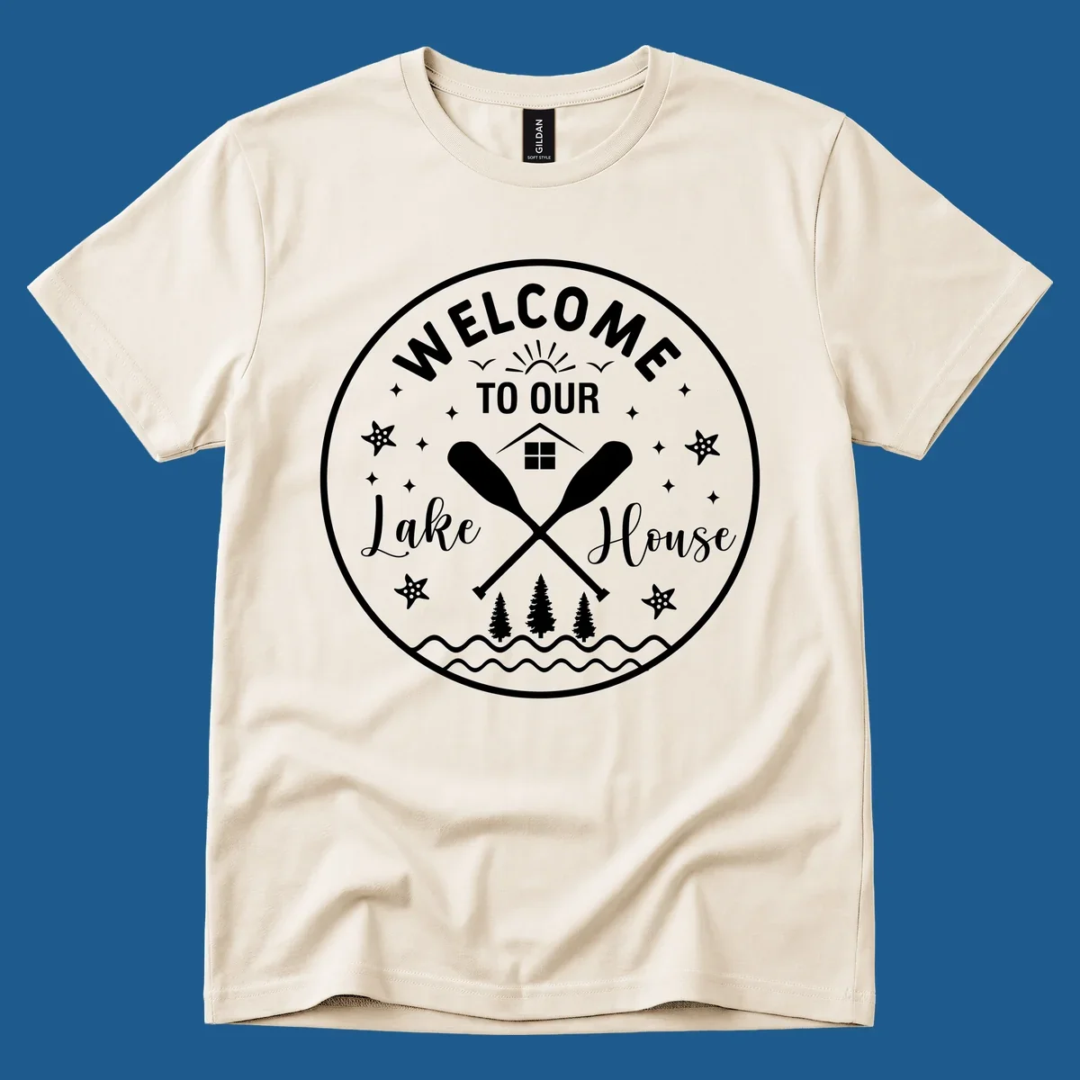 Welcome to our lake house circular design with oars, house, trees, and text.
