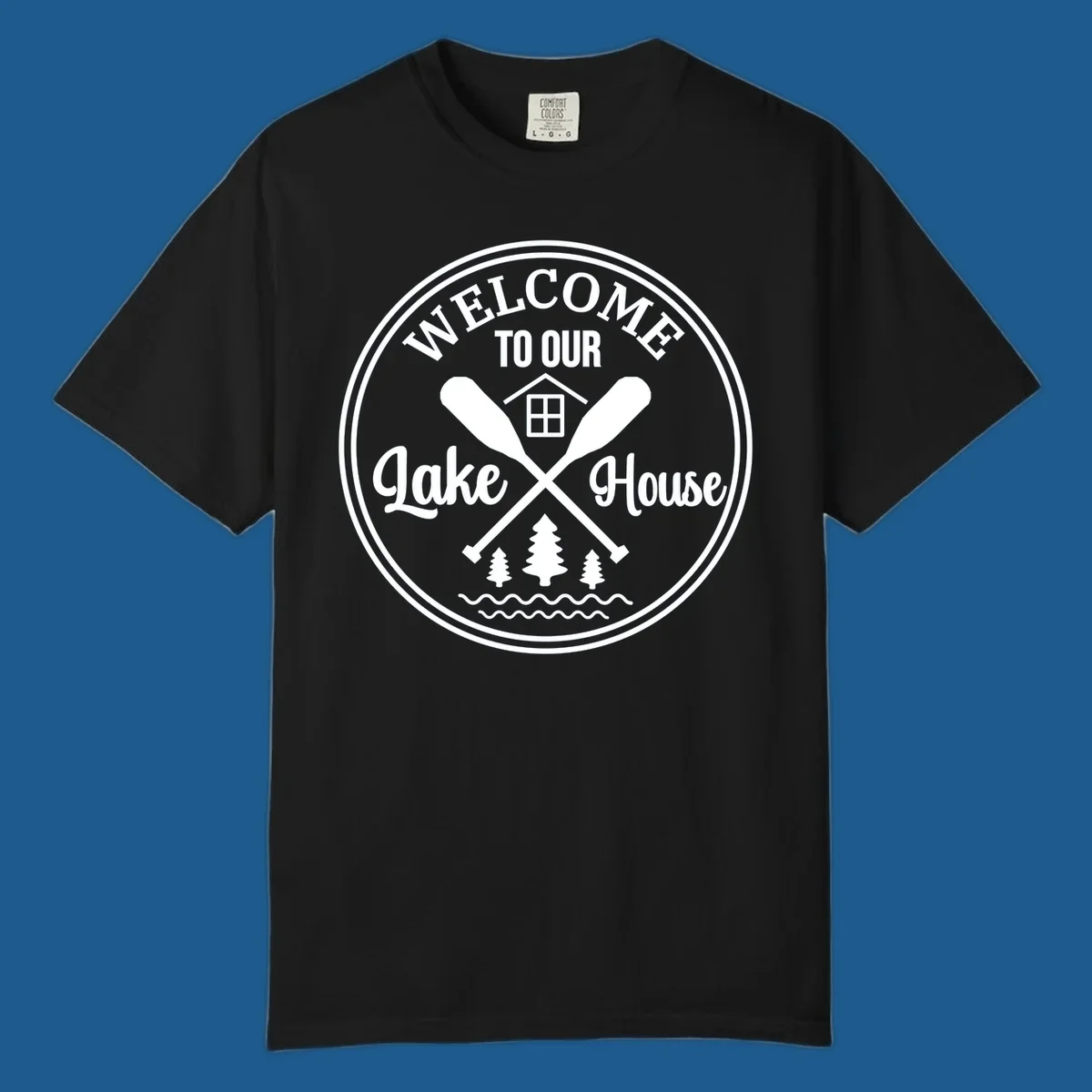 Circular badge design with text 'WELCOME TO OUR Lake House', crossed oars, house, trees, and waves.