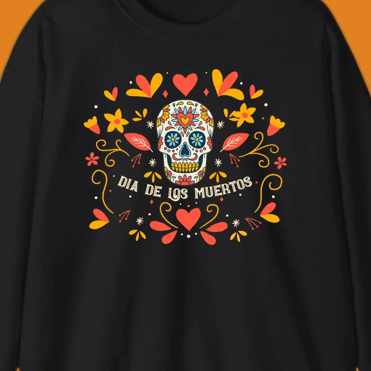 A colorful Día de los Muertos sugar skull with a heart on its forehead, surrounded by a symmetrical frame of red hearts, yellow flowers, and leaves, with 'DIA DE LOS MUERTOS' text below.