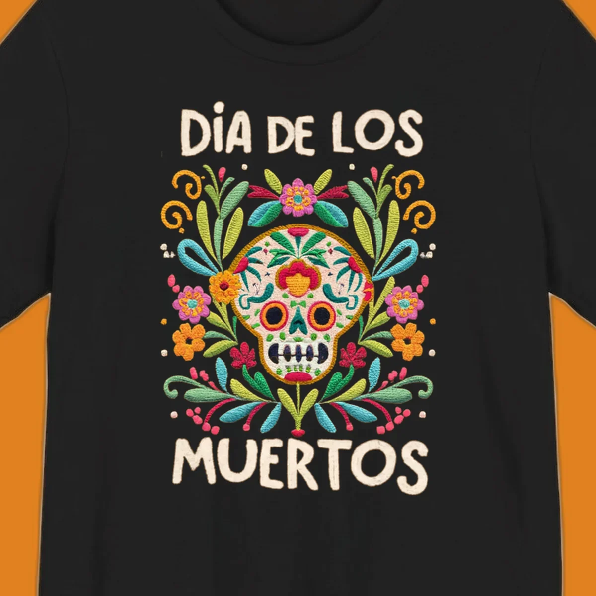 An embroidered-style Día de los Muertos sugar skull with colorful flowers and leaves, and the text "DÍA DE LOS MUERTOS".