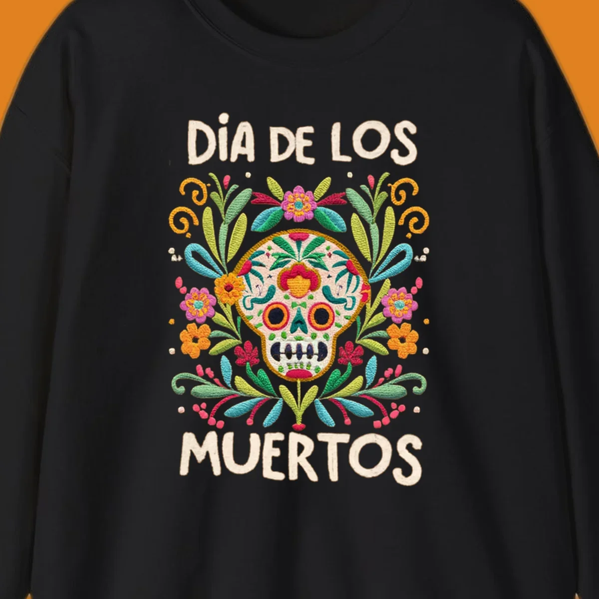An embroidered-style Día de los Muertos sugar skull with colorful flowers and leaves, and the text "DÍA DE LOS MUERTOS".