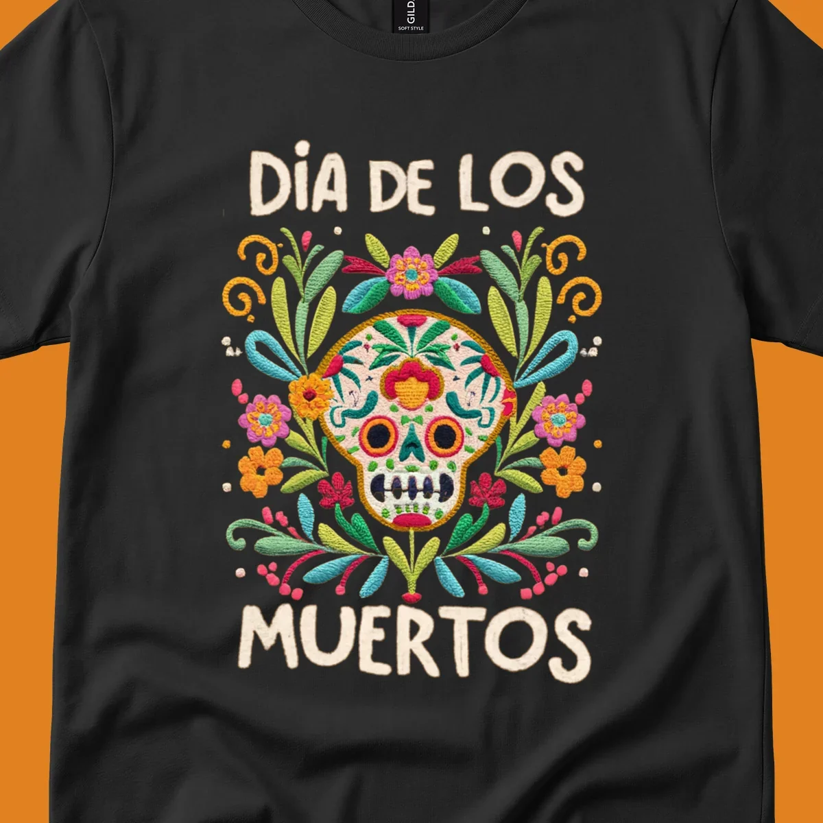 An embroidered-style Día de los Muertos sugar skull with colorful flowers and leaves, and the text "DÍA DE LOS MUERTOS".