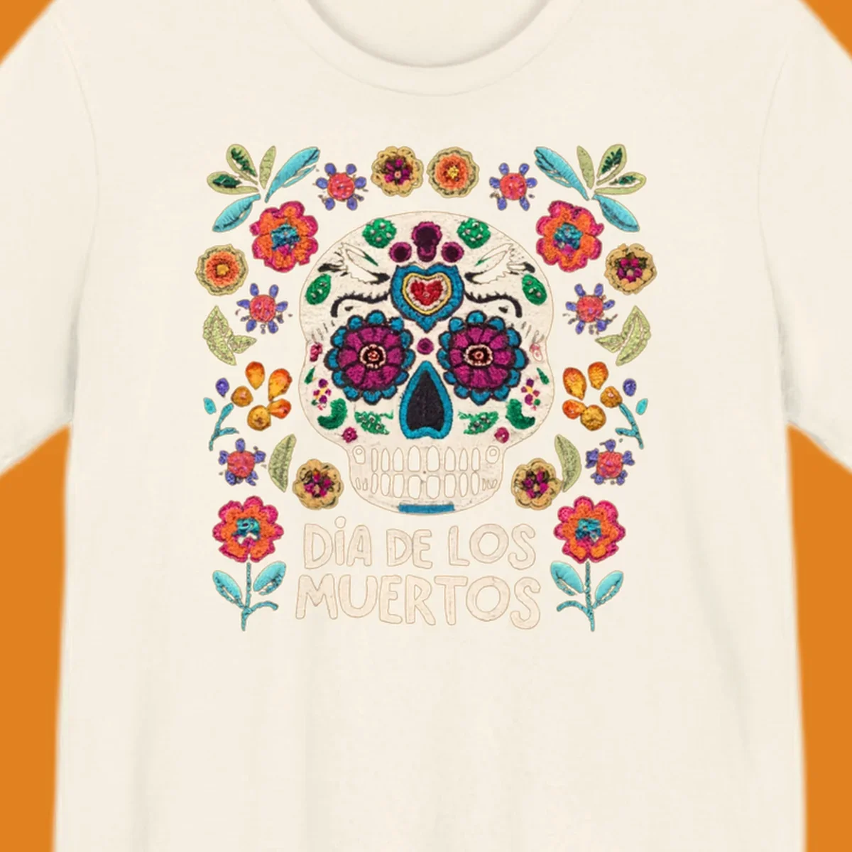 Embroidered-style Día de los Muertos sugar skull with colorful flowers and leaves, and text 'DÍA DE LOS MUERTOS'.