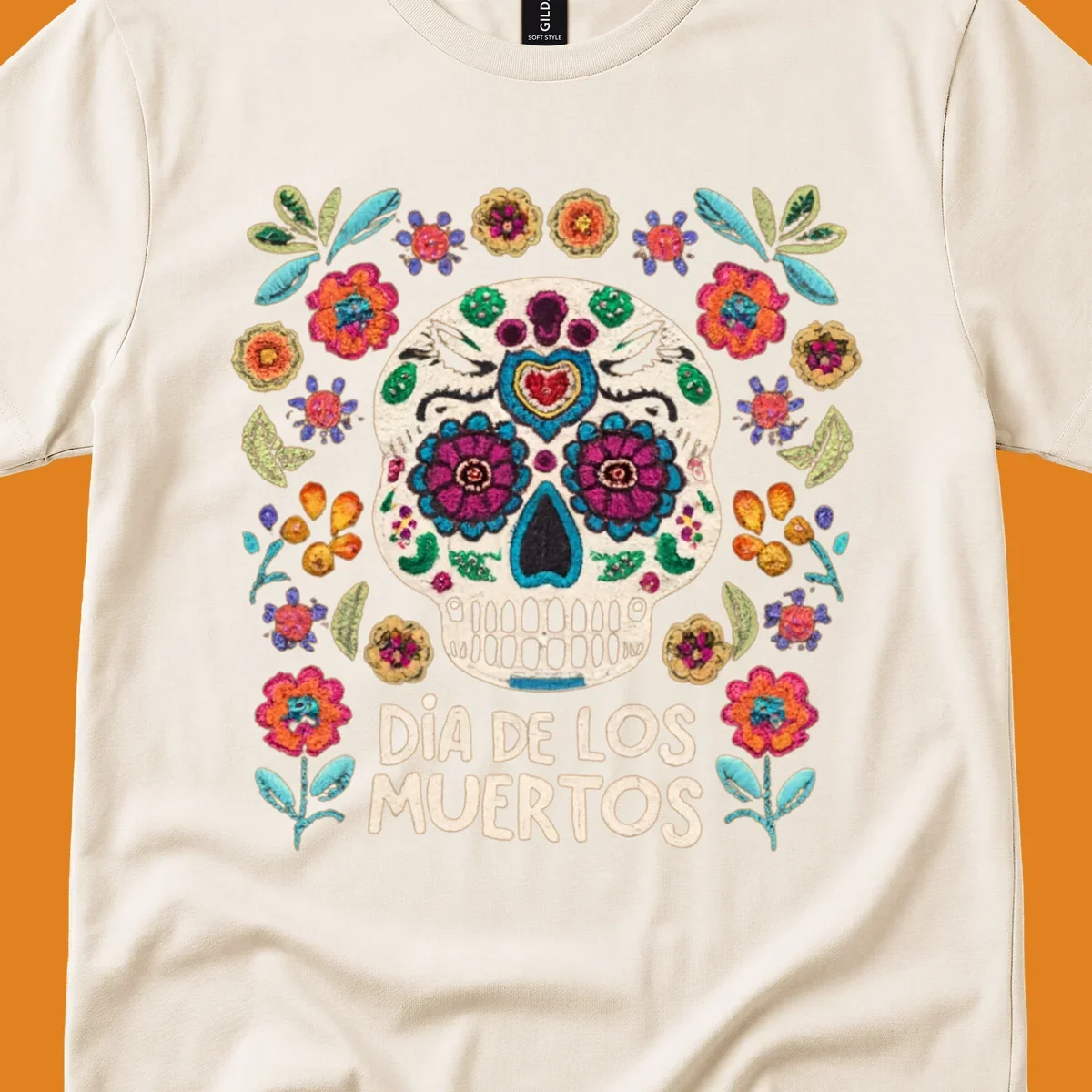 Embroidered-style Día de los Muertos sugar skull with colorful flowers and leaves, and text 'DÍA DE LOS MUERTOS'.