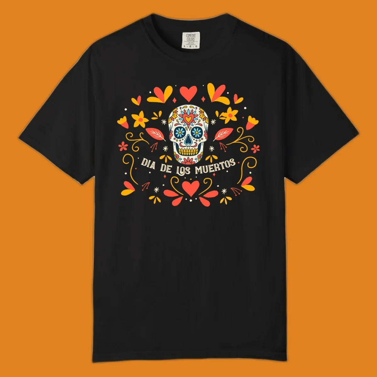 A colorful Día de los Muertos sugar skull with a heart on its forehead, surrounded by a symmetrical frame of red hearts, yellow flowers, and leaves, with 'DIA DE LOS MUERTOS' text below.