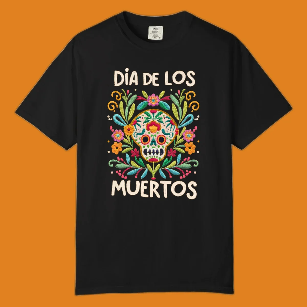 An embroidered-style Día de los Muertos sugar skull with colorful flowers and leaves, and the text "DÍA DE LOS MUERTOS".