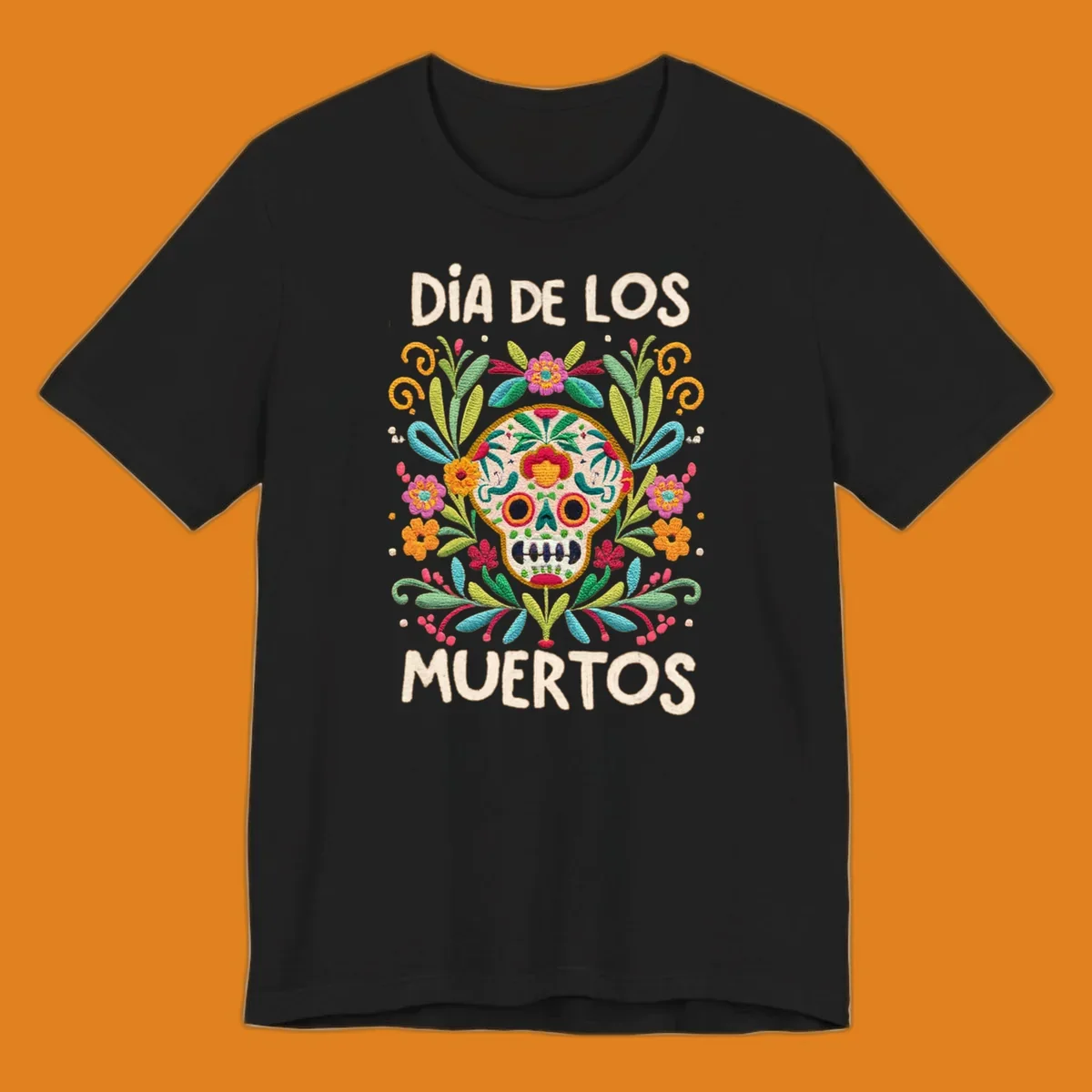 An embroidered-style Día de los Muertos sugar skull with colorful flowers and leaves, and the text "DÍA DE LOS MUERTOS".