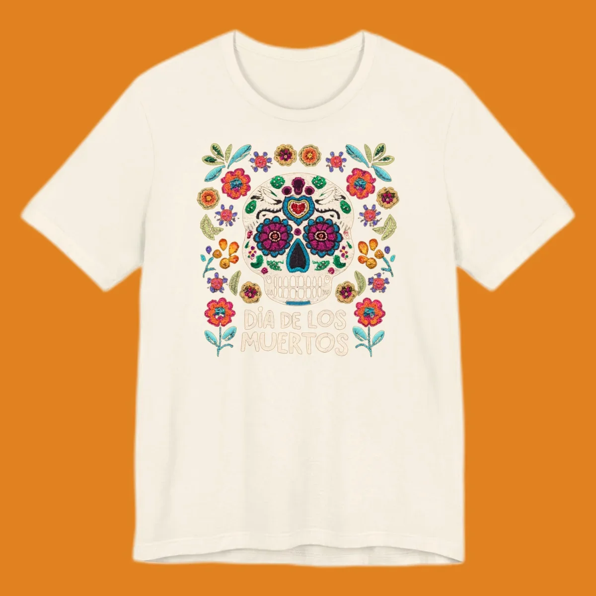 Embroidered-style Día de los Muertos sugar skull with colorful flowers and leaves, and text 'DÍA DE LOS MUERTOS'.