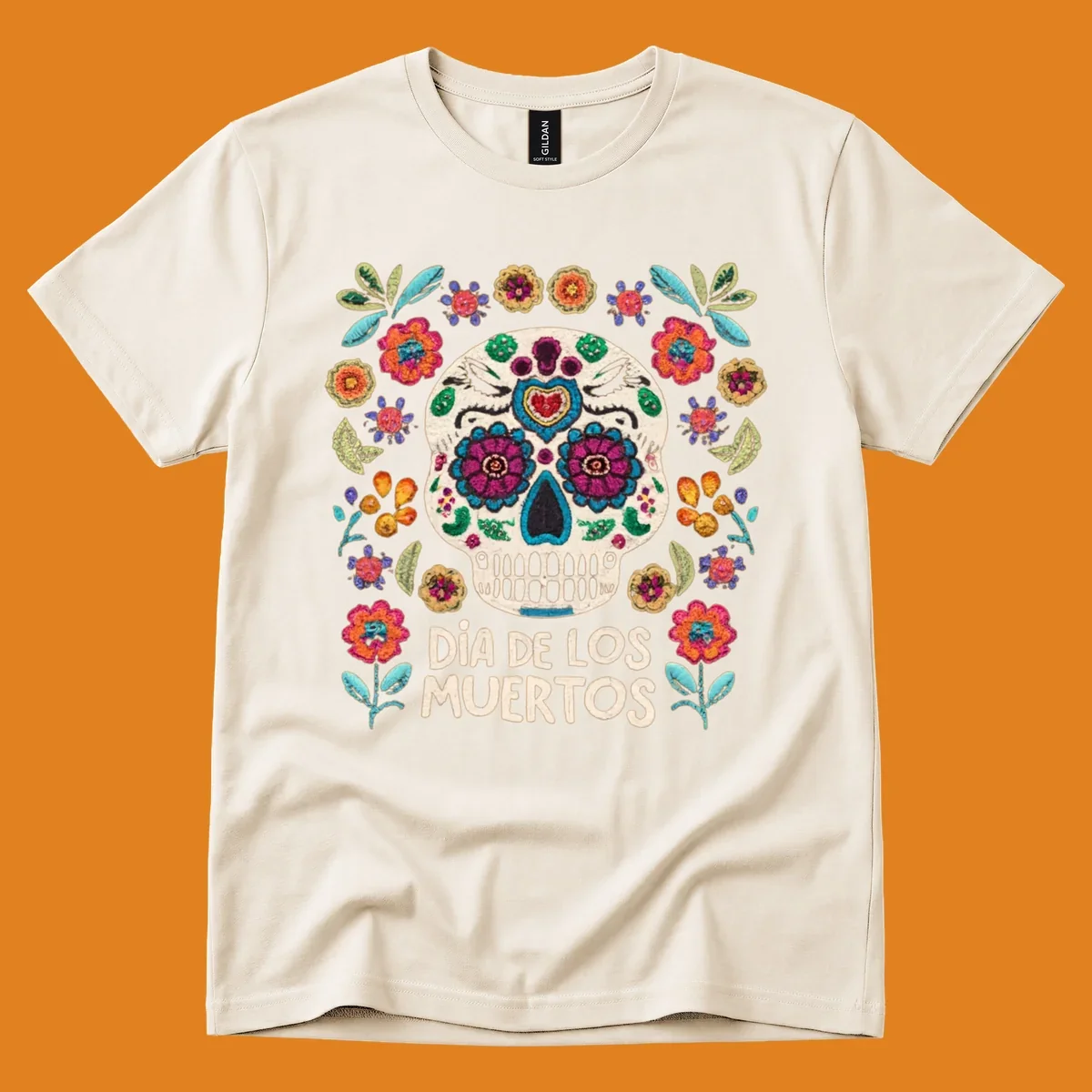 Embroidered-style Día de los Muertos sugar skull with colorful flowers and leaves, and text 'DÍA DE LOS MUERTOS'.