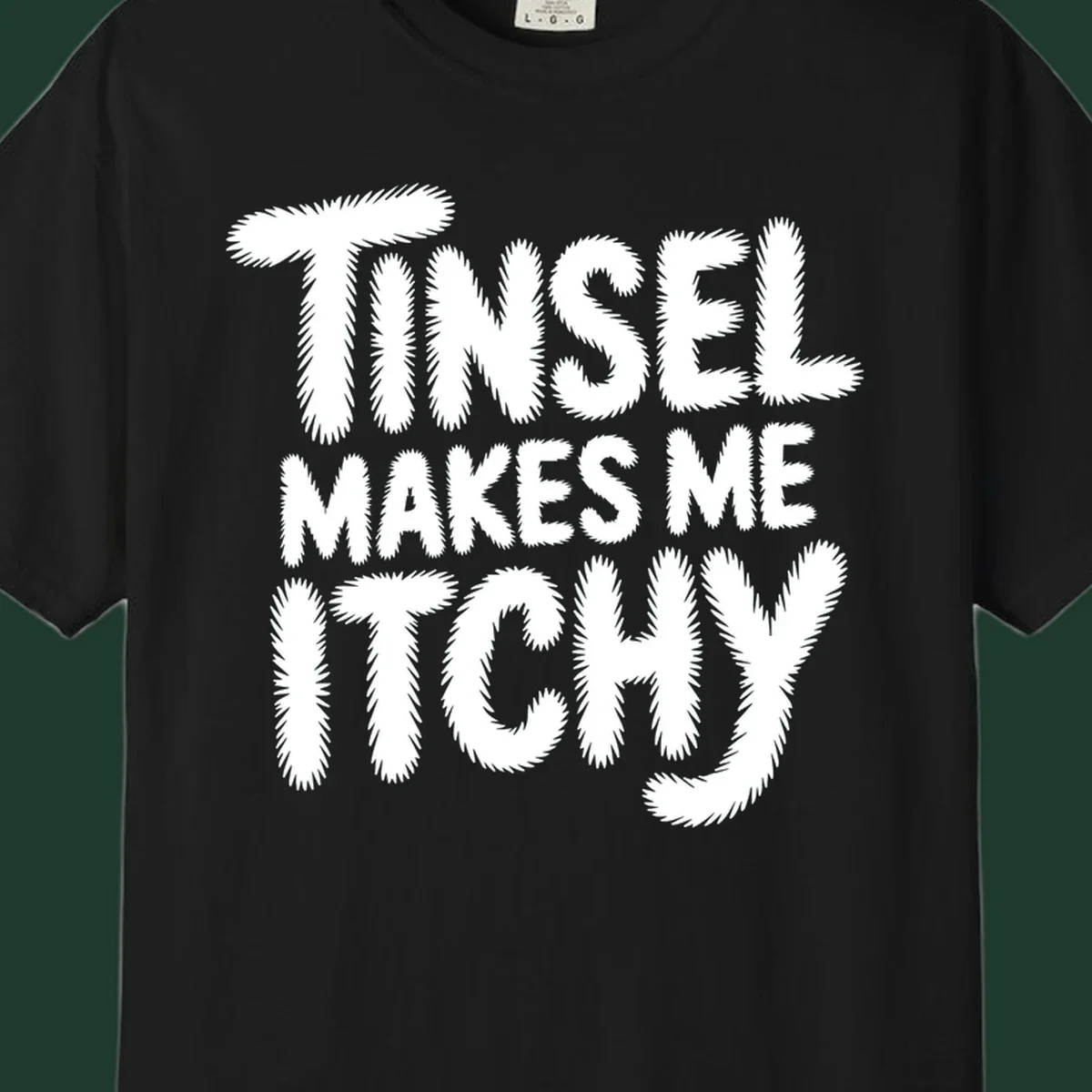 Text design reading "Tinsel Makes Me Itchy" in a fuzzy font.