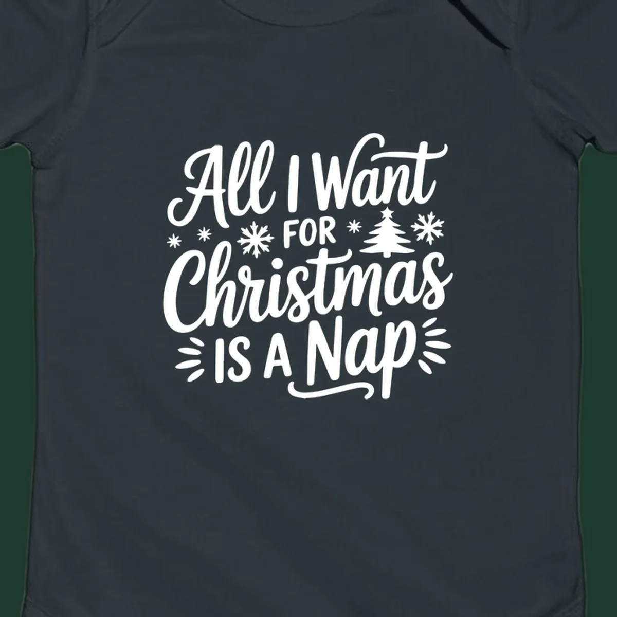 All I Want For Christmas Is A Nap typographic design with snowflakes and a Christmas tree.