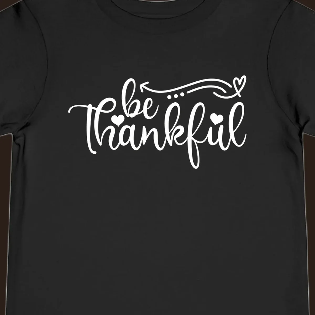White script text 'be thankful' with hearts and decorative swirls for Thanksgiving.