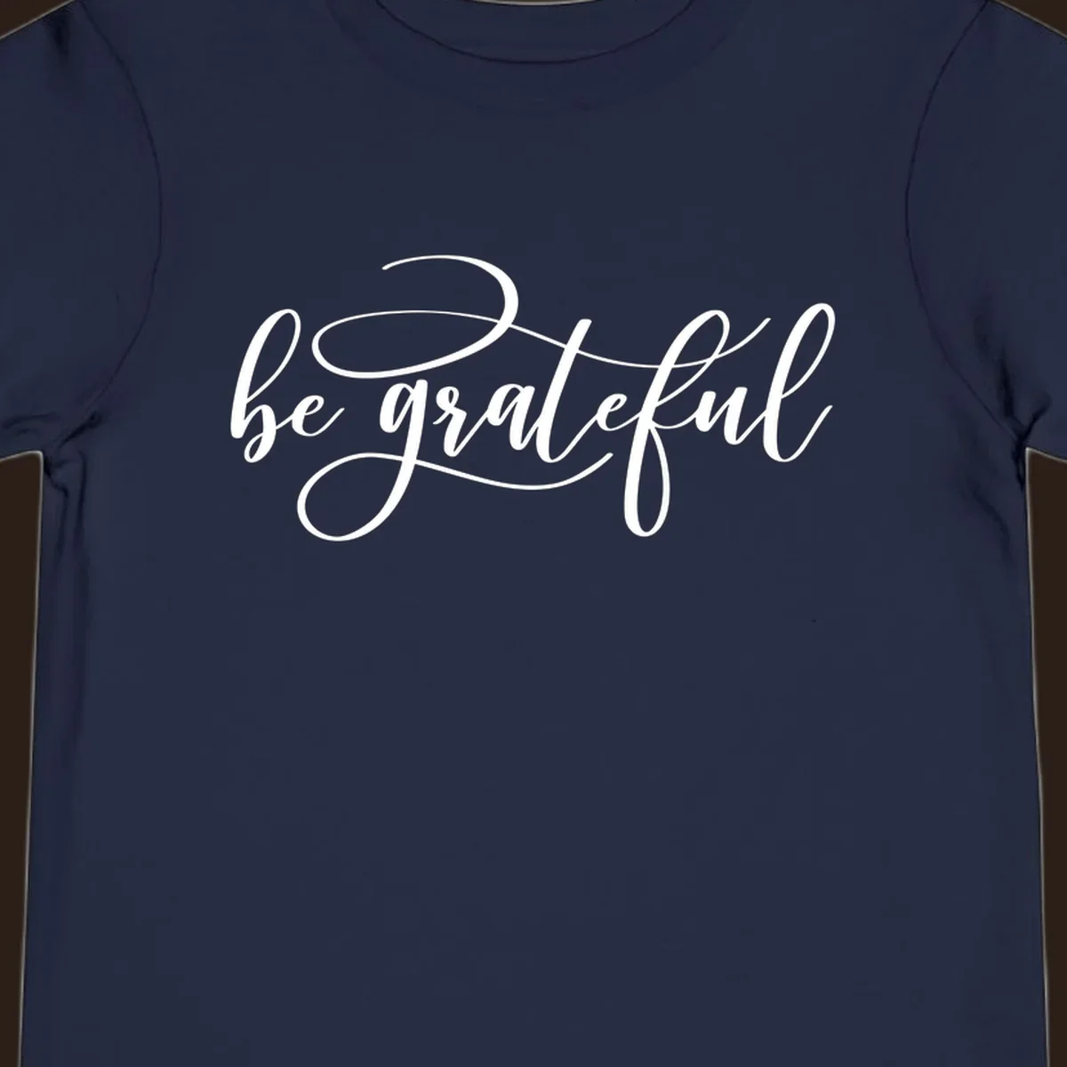 White script text that says 'be grateful' on a black background.