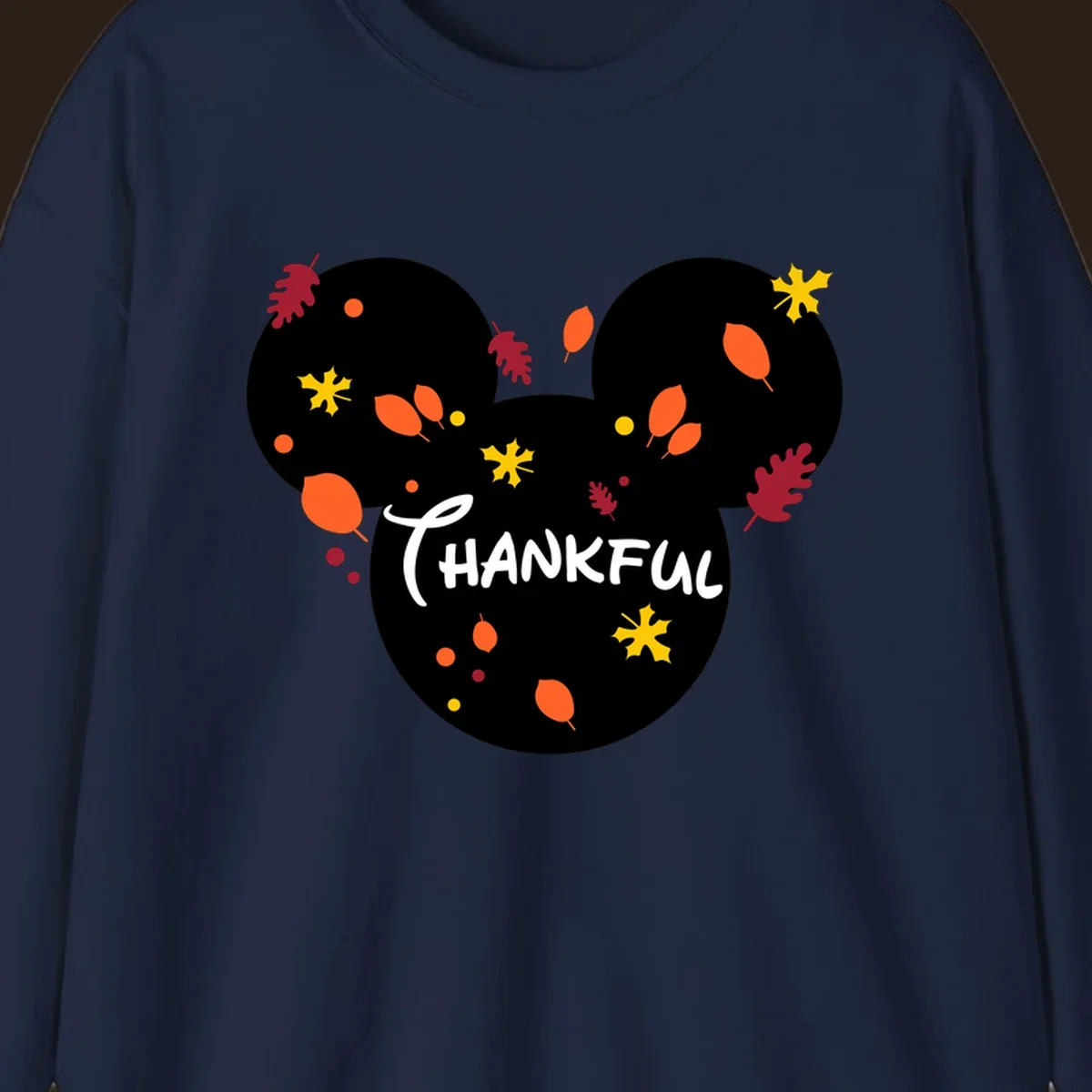 Mickey ears shape with fall leaves and the word THANKFUL in white text.