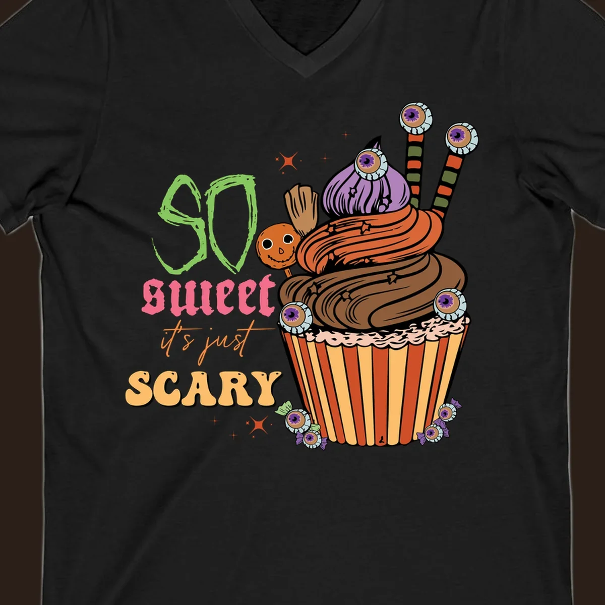 Halloween cupcake illustration with text 'So Sweet It's Just Scary', featuring candy eyeballs and a ghost lollipop.