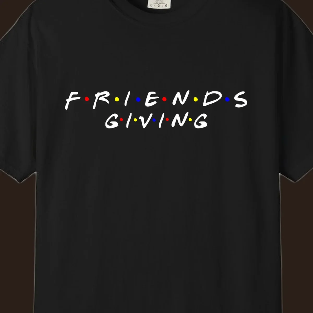 Friendsgiving typography design in white with red, yellow, and blue dots.