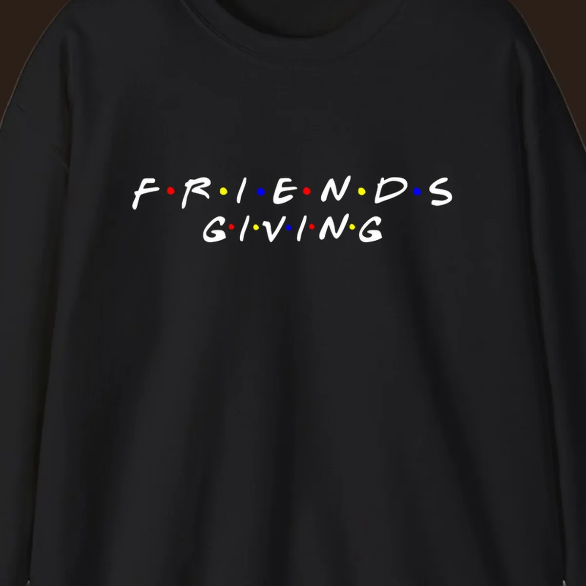 Friendsgiving typography design in white with red, yellow, and blue dots.
