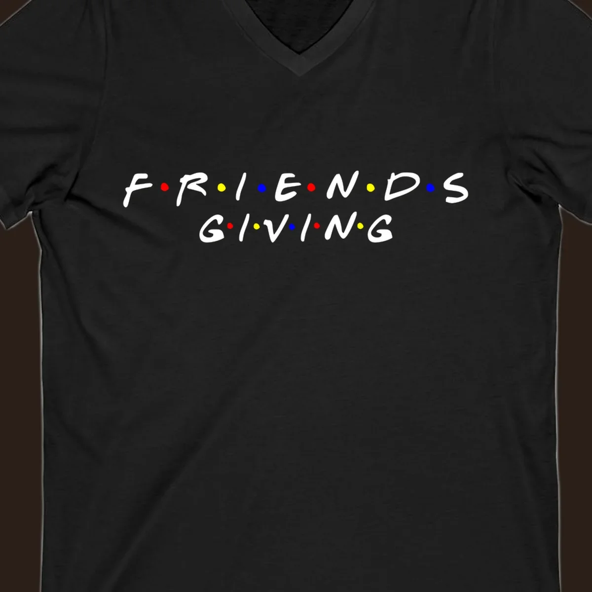 Friendsgiving typography design in white with red, yellow, and blue dots.