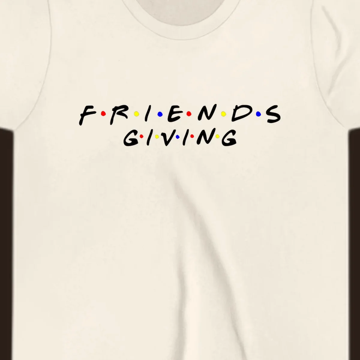 Friendsgiving typography design in white with red, yellow, and blue dots.