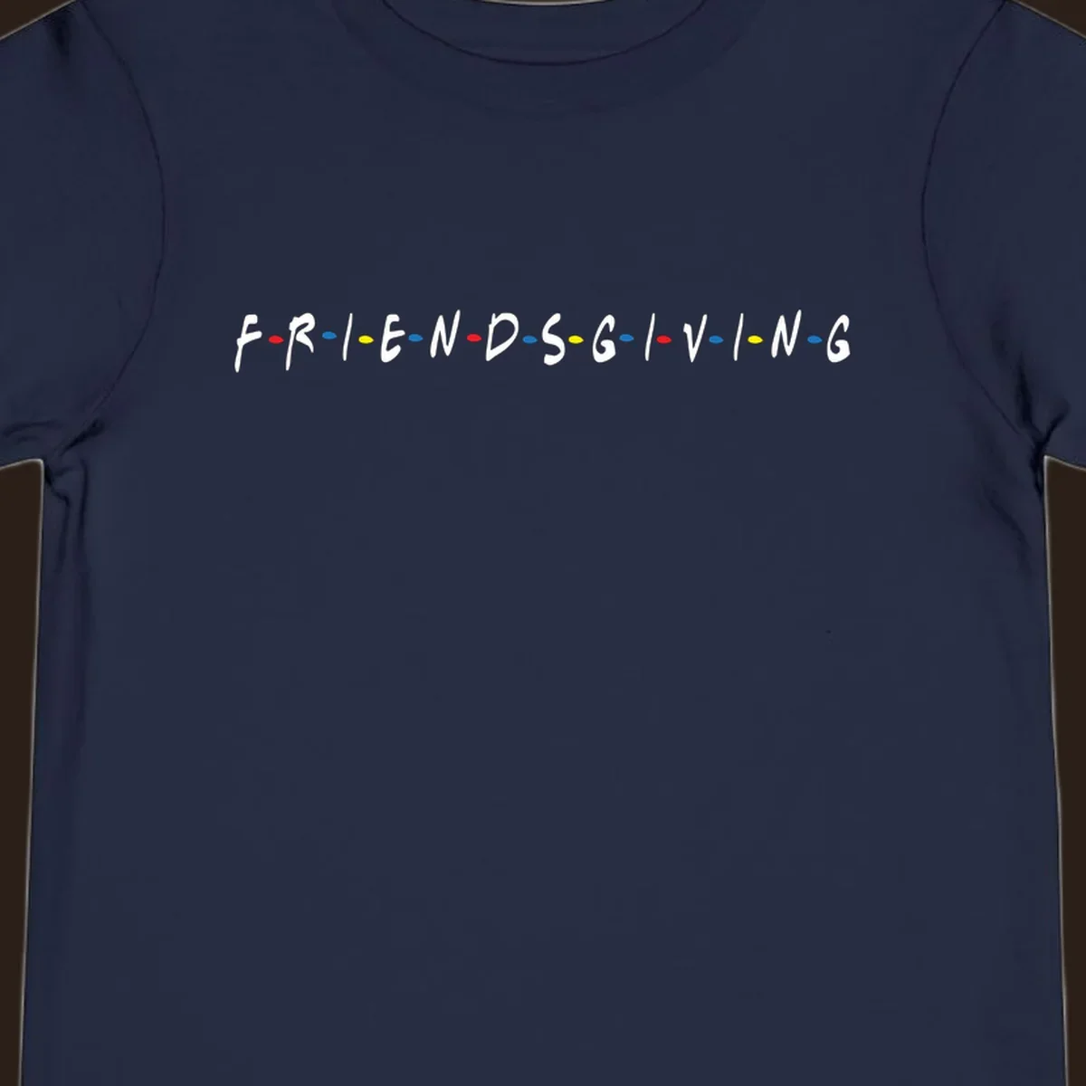 Friendsgiving typography design with white letters and colored dots on a black background.