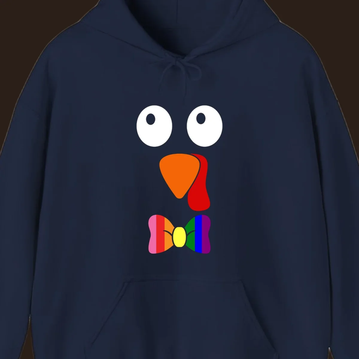 Cartoon turkey face with rainbow bowtie, featuring large eyes, orange beak, and red wattle. Thanksgiving holiday graphic.