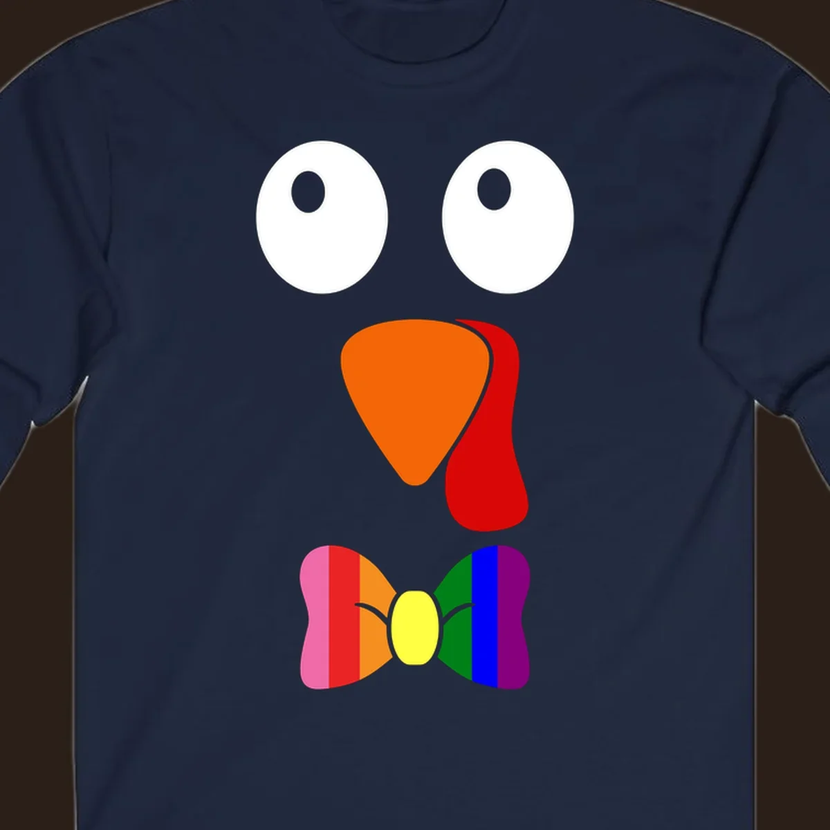 Cartoon turkey face with rainbow bowtie, featuring large eyes, orange beak, and red wattle. Thanksgiving holiday graphic.