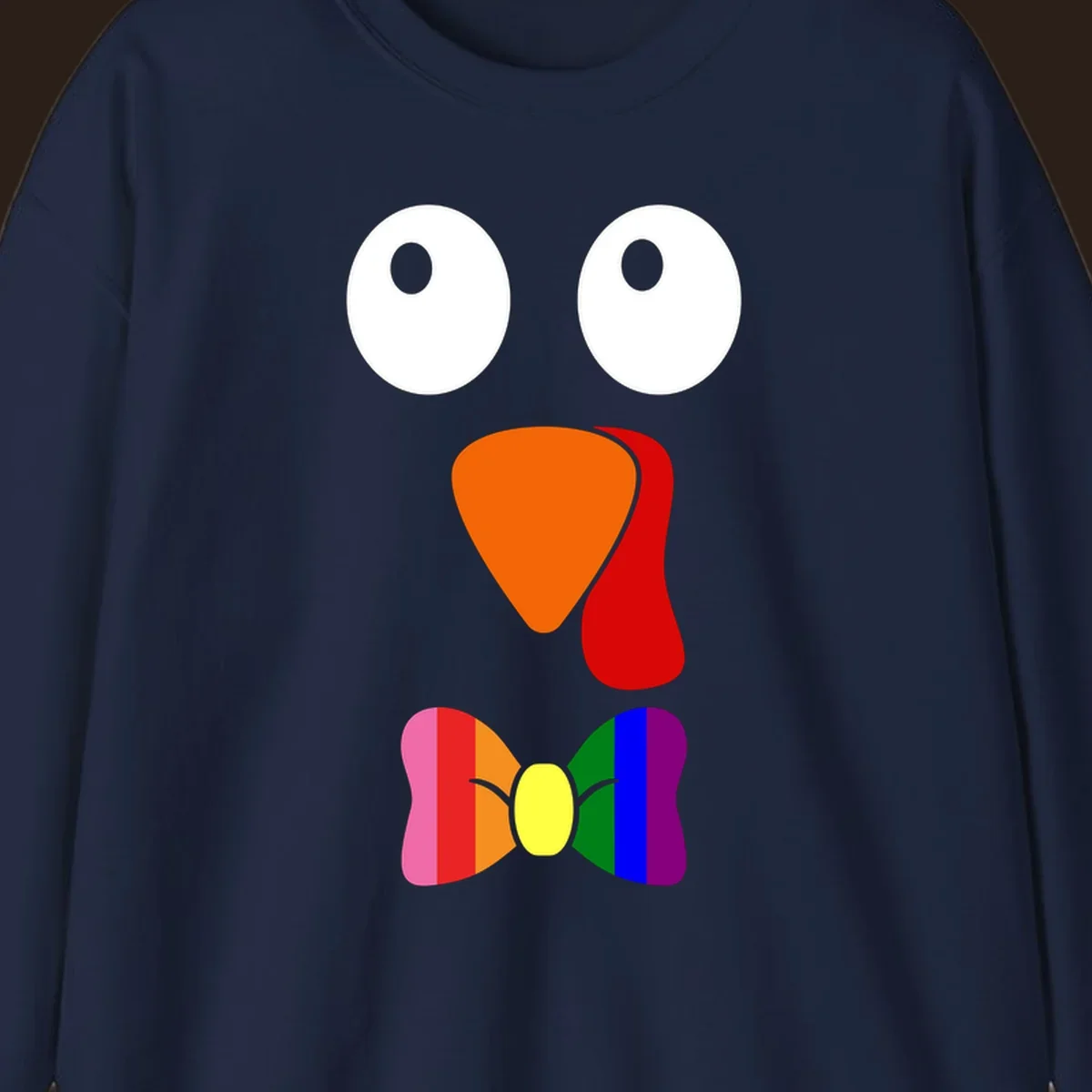 Cartoon turkey face with rainbow bowtie, featuring large eyes, orange beak, and red wattle. Thanksgiving holiday graphic.