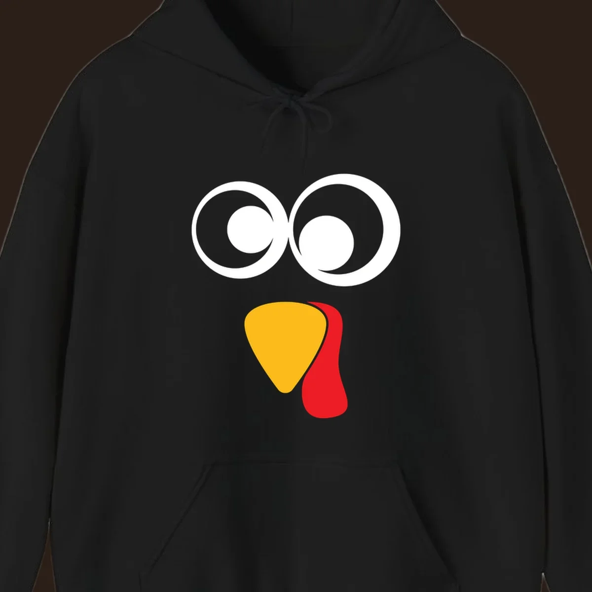 Googly-eyed turkey face illustration with yellow beak and red wattle.