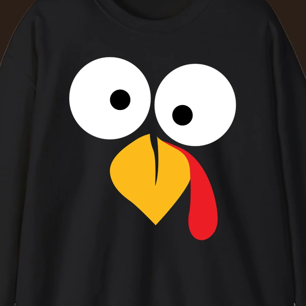 Googly-eyed turkey face illustration with yellow beak and red wattle.