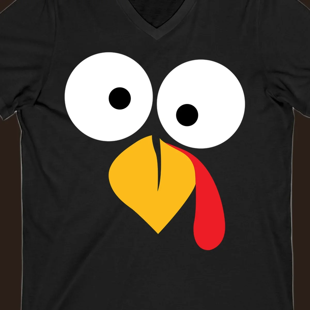 Googly-eyed turkey face illustration with yellow beak and red wattle.