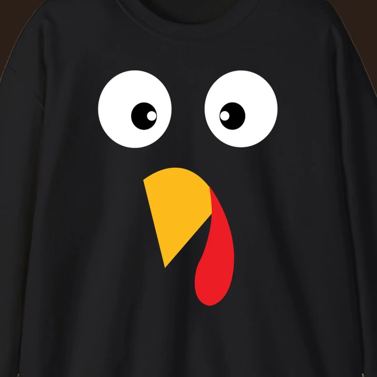 Googly eyed turkey face illustration with yellow beak and red wattle on black background.