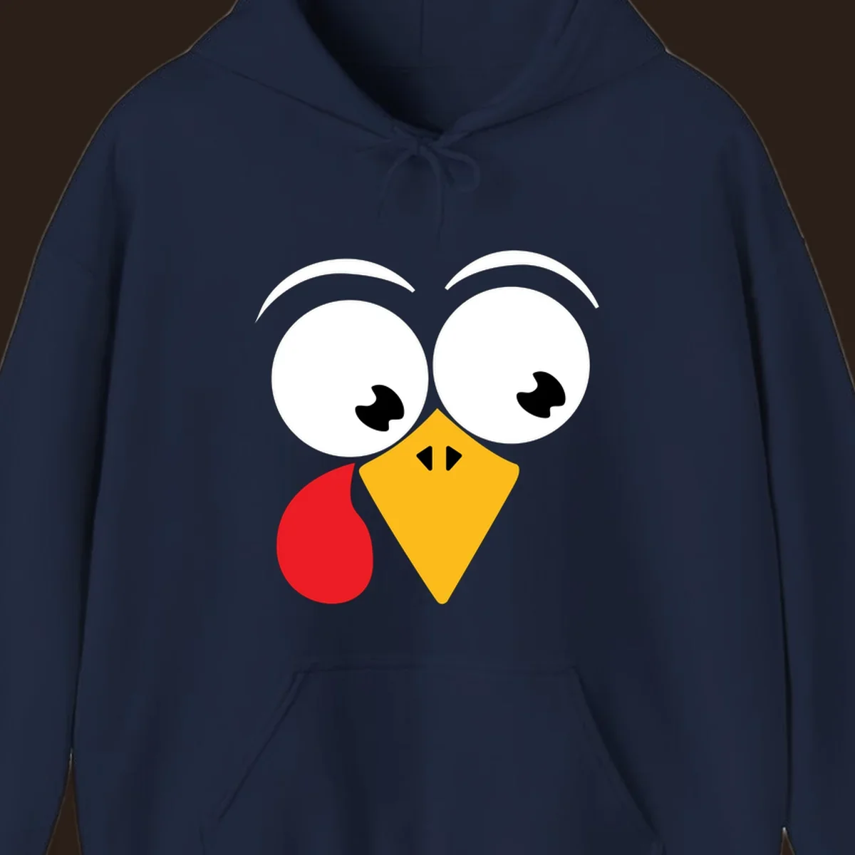 Googly eyed turkey face with yellow beak and red wattle on black background.