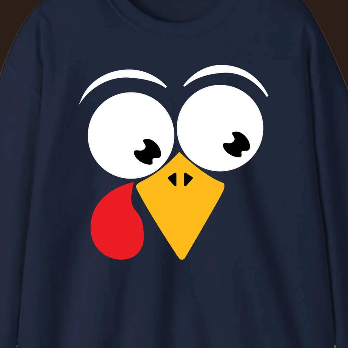 Googly eyed turkey face with yellow beak and red wattle on black background.
