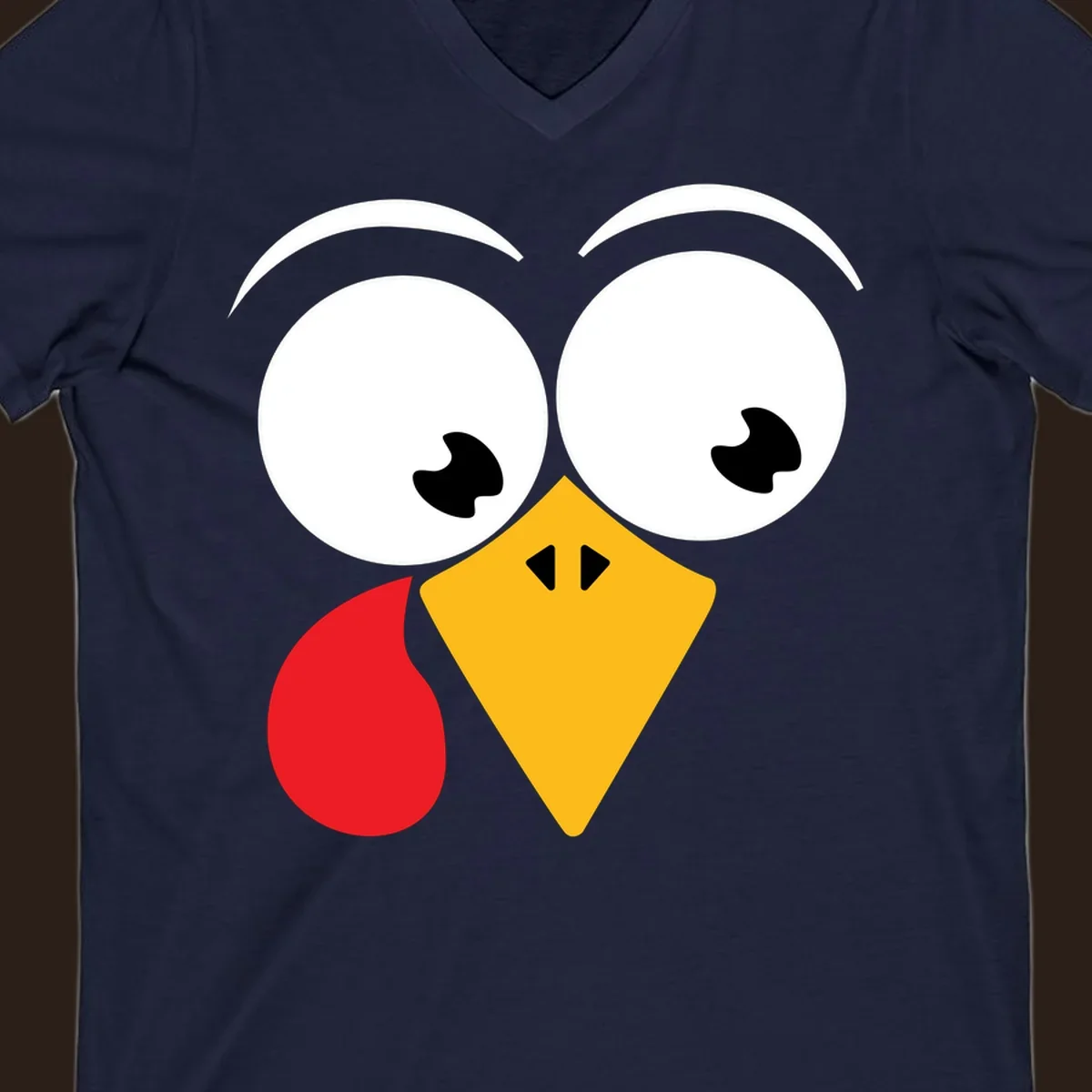 Googly eyed turkey face with yellow beak and red wattle on black background.