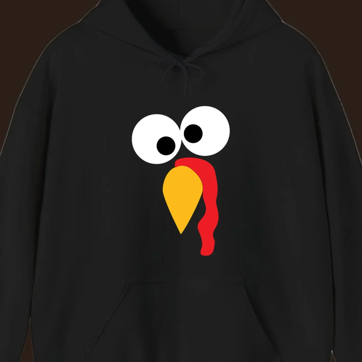 Googly-eyed turkey face illustration with yellow beak and red wattle.
