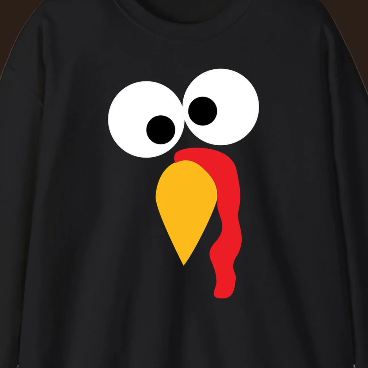 Googly-eyed turkey face illustration with yellow beak and red wattle.