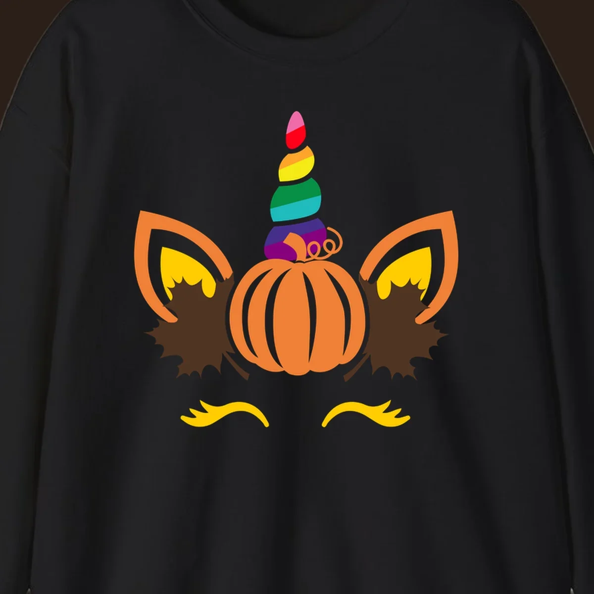 Illustration of a unicorn face made from a pumpkin with a rainbow horn and autumn leaves, on a black background.
