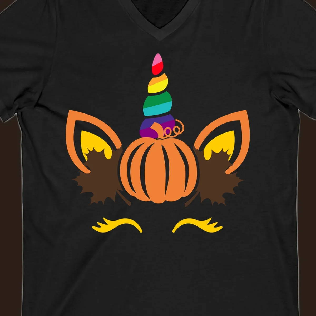 Illustration of a unicorn face made from a pumpkin with a rainbow horn and autumn leaves, on a black background.