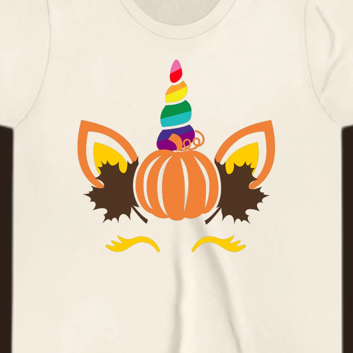 Illustration of a unicorn face made from a pumpkin with a rainbow horn and autumn leaves, on a black background.