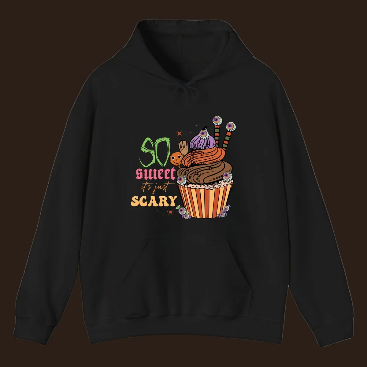 Halloween cupcake illustration with text 'So Sweet It's Just Scary', featuring candy eyeballs and a ghost lollipop.