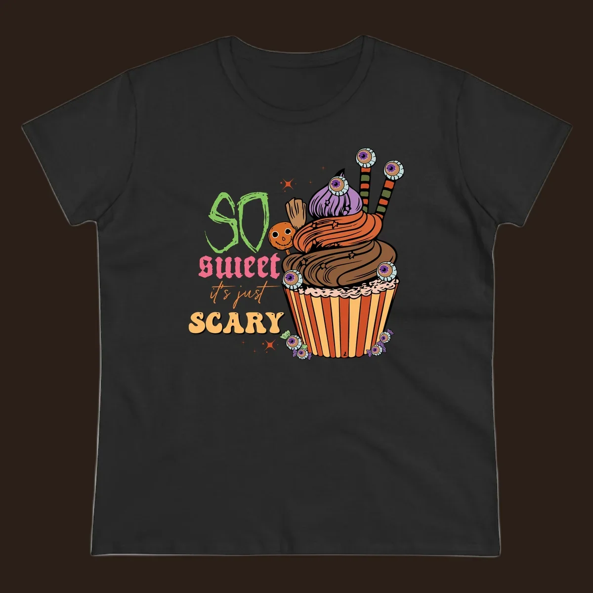 Halloween cupcake illustration with text 'So Sweet It's Just Scary', featuring candy eyeballs and a ghost lollipop.