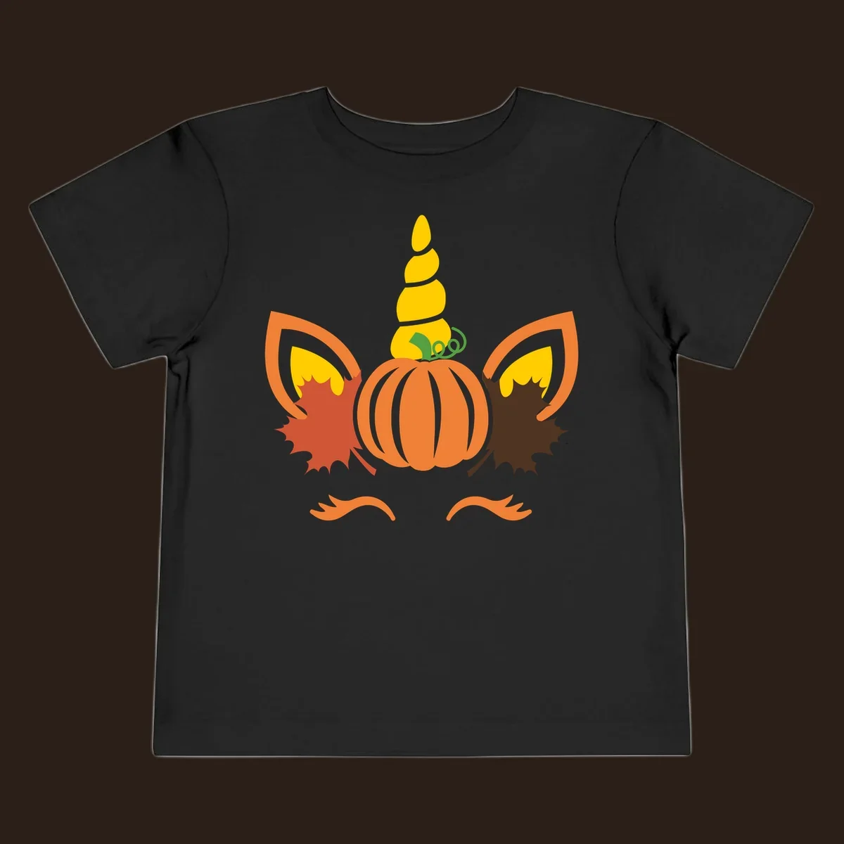 Autumn unicorn pumpkin face with fall leaves graphic.