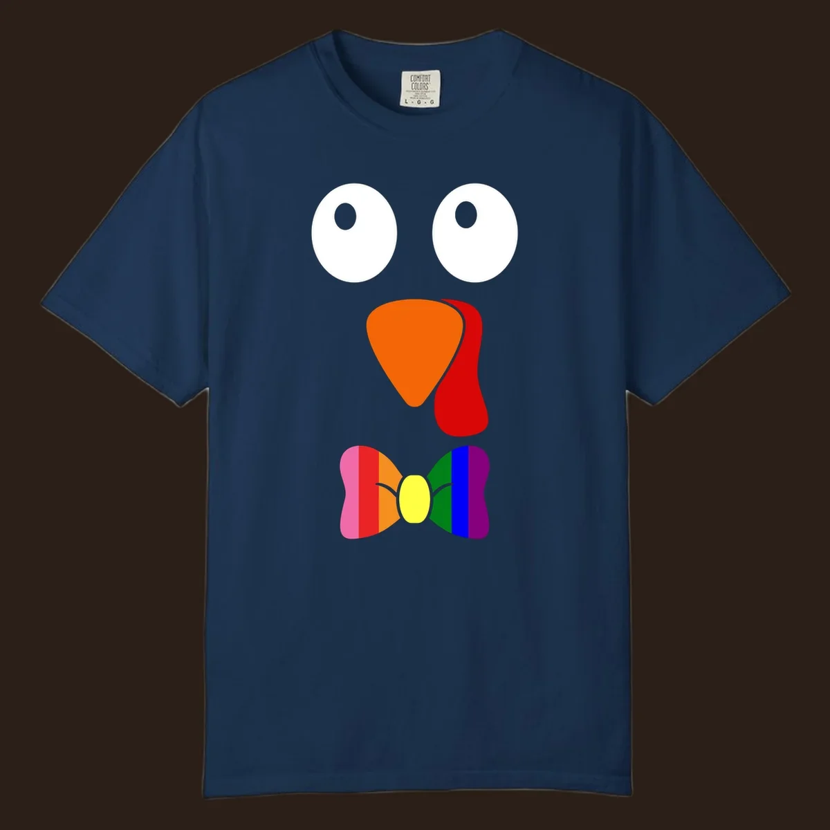 Cartoon turkey face with rainbow bowtie, featuring large eyes, orange beak, and red wattle. Thanksgiving holiday graphic.