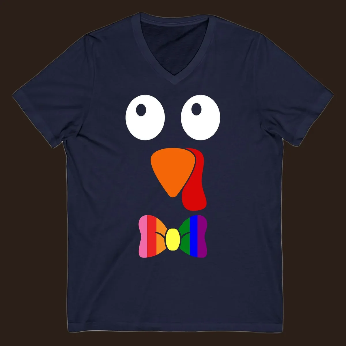 Cartoon turkey face with rainbow bowtie, featuring large eyes, orange beak, and red wattle. Thanksgiving holiday graphic.
