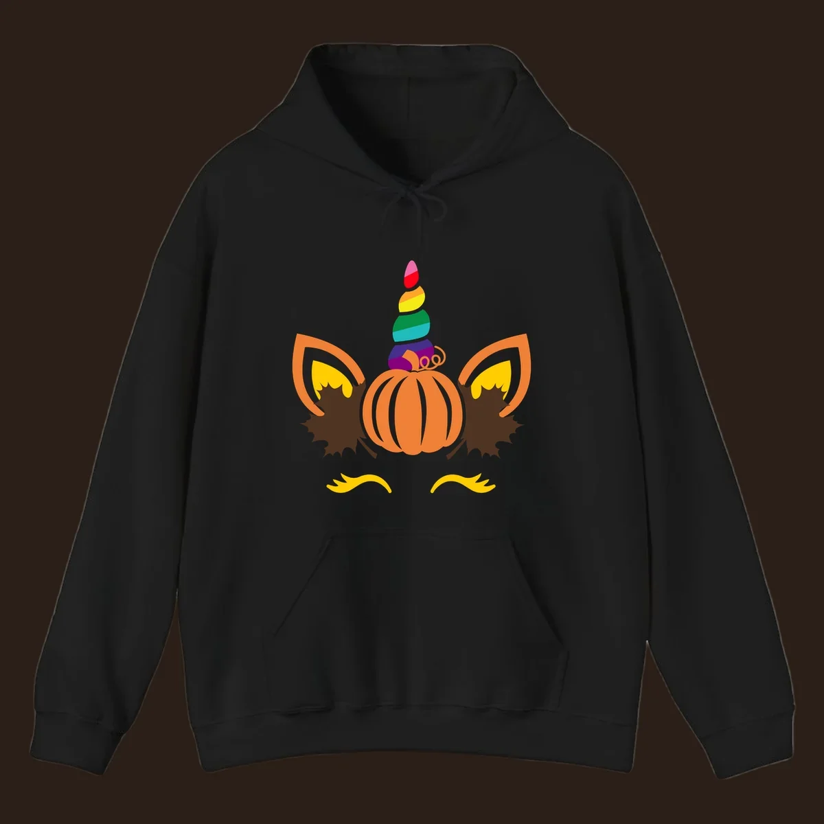 Illustration of a unicorn face made from a pumpkin with a rainbow horn and autumn leaves, on a black background.