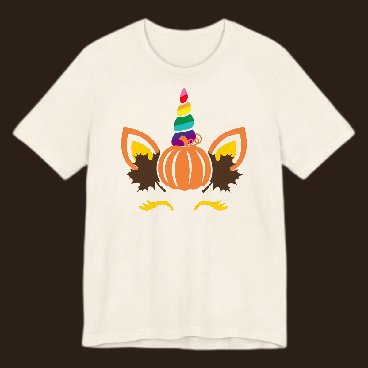 Illustration of a unicorn face made from a pumpkin with a rainbow horn and autumn leaves, on a black background.