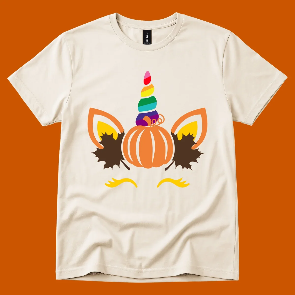 Illustration of a unicorn face made from a pumpkin with a rainbow horn and autumn leaves, on a black background.