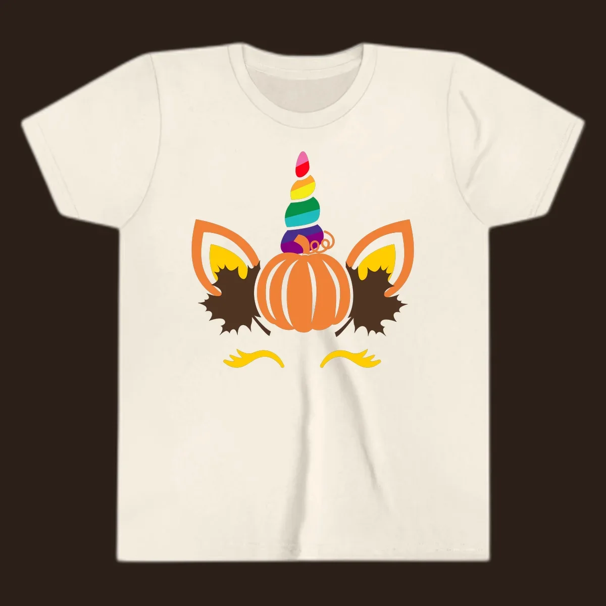 Illustration of a unicorn face made from a pumpkin with a rainbow horn and autumn leaves, on a black background.
