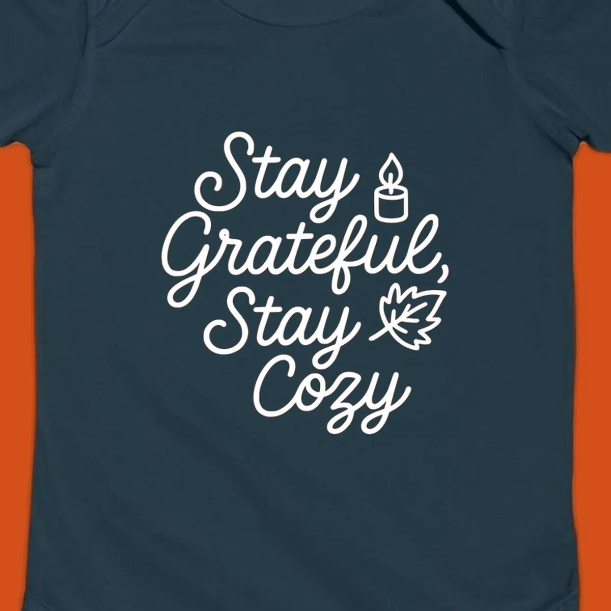 Text design with 'Stay Grateful, Stay Cozy' phrase, candle, and leaf for grateful-cozy-fall theme.