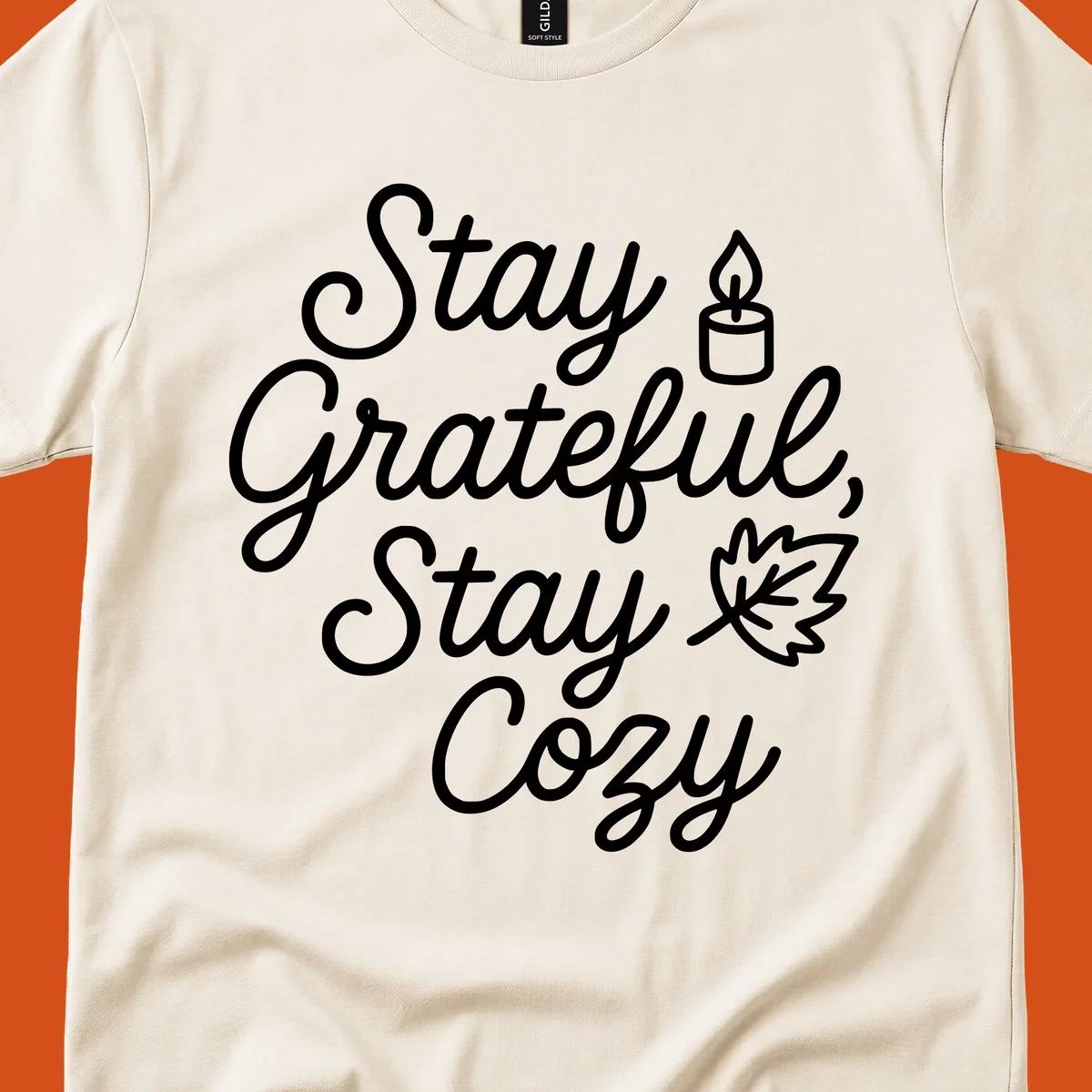 Text design with 'Stay Grateful, Stay Cozy' phrase, candle, and leaf for grateful-cozy-fall theme.